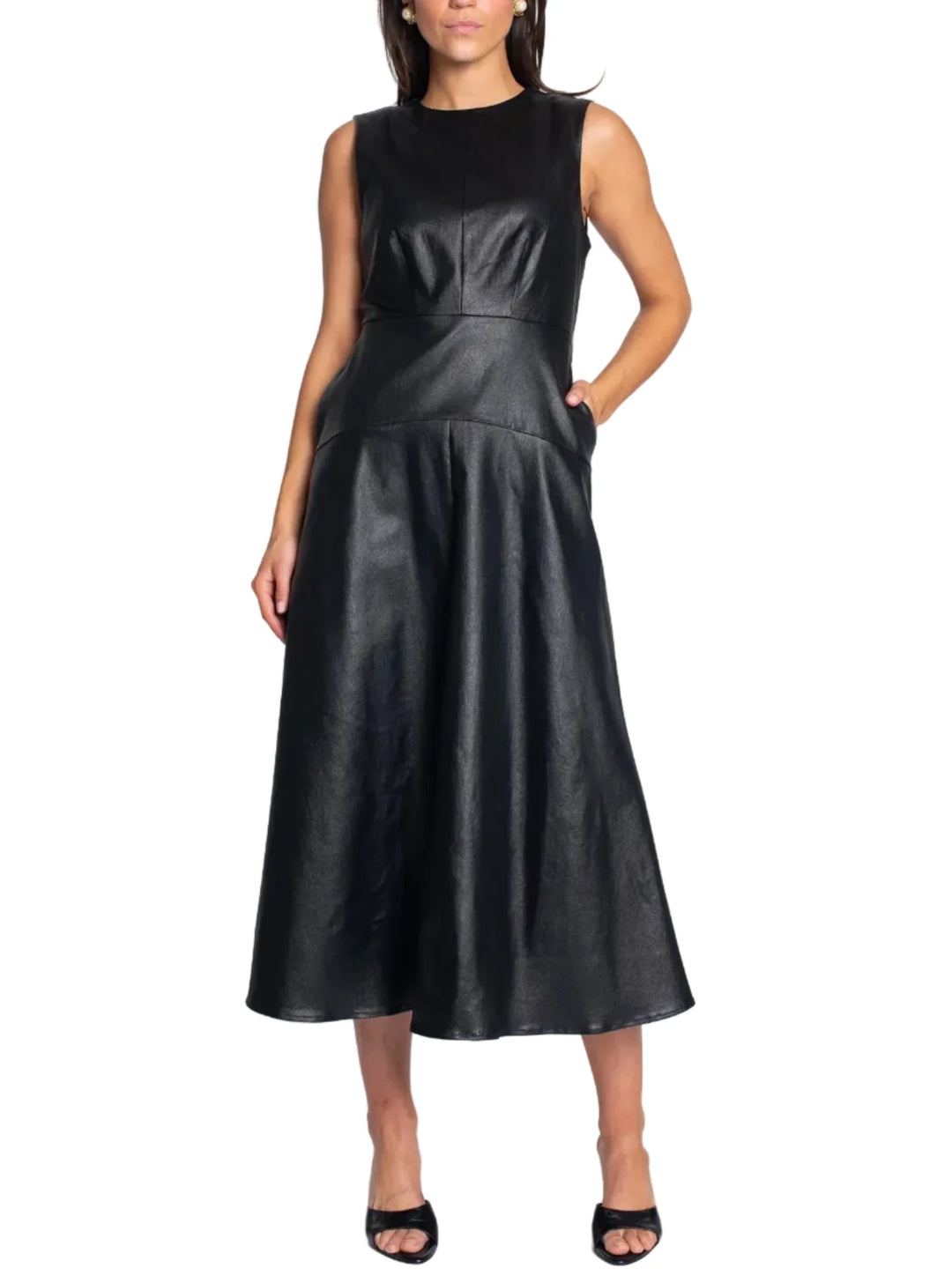 A woman modeling a sleeveless black midi dress with a structured bodice and flared skirt, paired with black heeled sandals, against a light gray studio background.