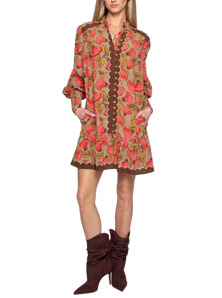 A woman modeling a bohemian-style mini dress with a brown paisley print, a brown button-down front, and a scalloped hem, paired with dark brown suede ankle boots against a white studio background.