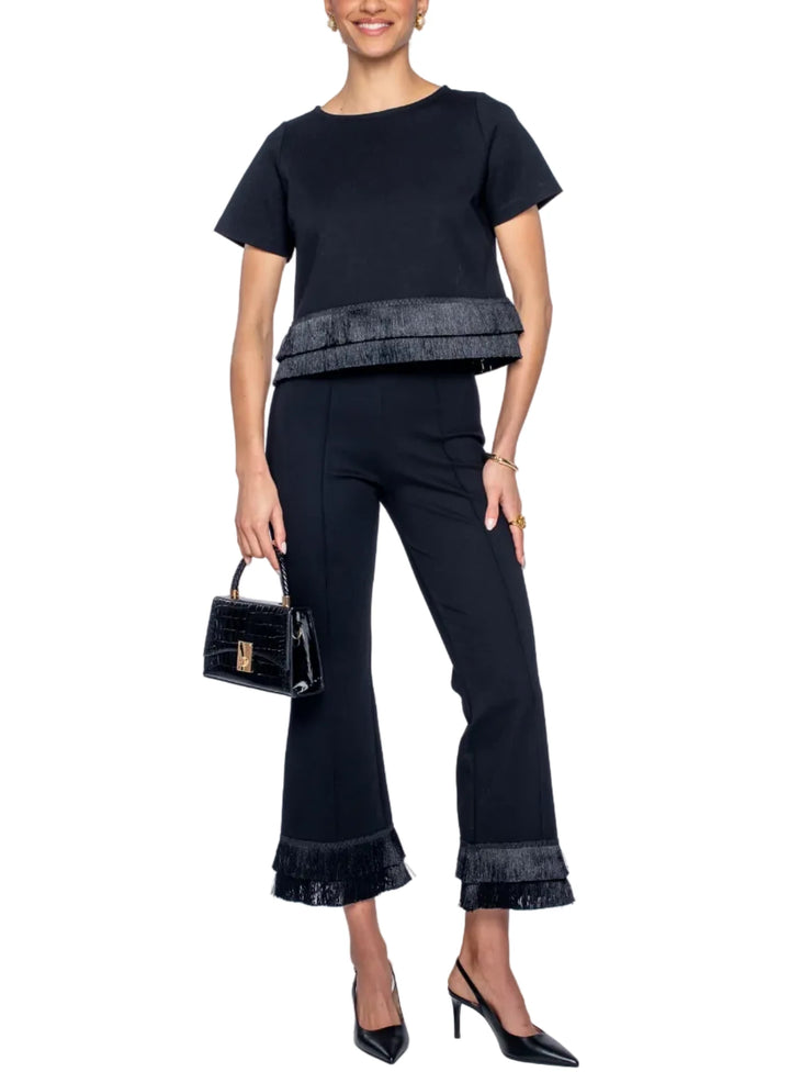 Woman wearing a black outfit with ruffled details on a white background