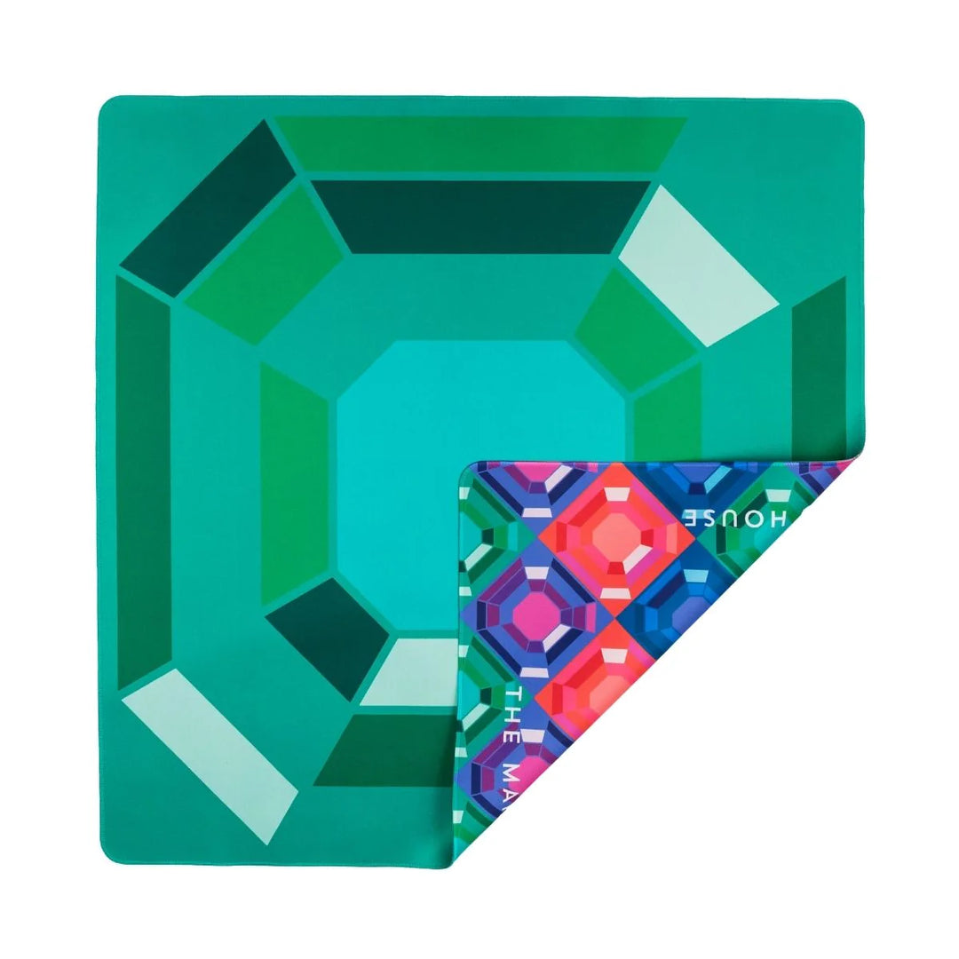 Bring twice the brilliance to your game with our Emerald Gem Double-Sided Mahjong Mat. One side features one large faceted emerald and the other side a pattern of all of our Jewel Collection jewels. This mat creates a stunning backdrop, especially to our Jewels! Emerald House Tiles, but is designed to mix-and-match with any tiles in the Jewels House Collection, adding many interesting facets to every jewel of a game.