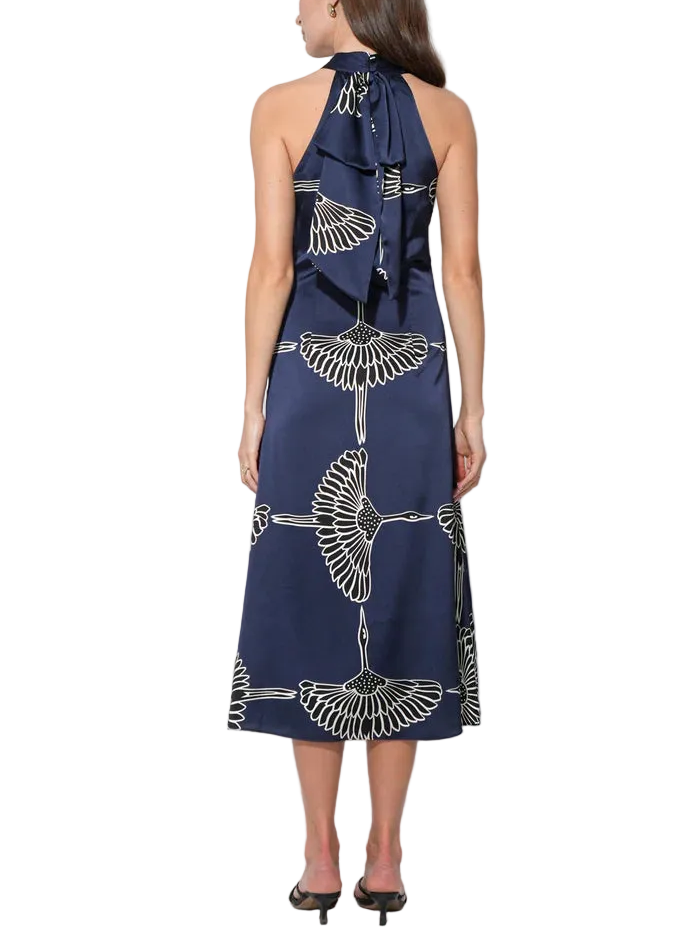 Crafted from a luxurious satin fabric, the dress offers a beautiful sheen and a fluid drape that moves gracefully with the wearer. The silhouette features a halter neckline, which elegantly frames the shoulders, and is finished with a delicate ribbon tie closure at the neck.