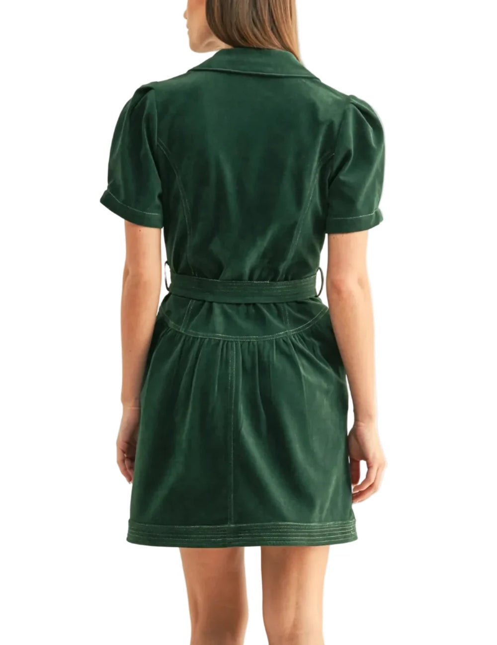 A woman viewed from the back wearing a dark green corduroy mini dress with short puff sleeves, a matching waist belt, and contrast stitching, set against a plain off-white studio background.