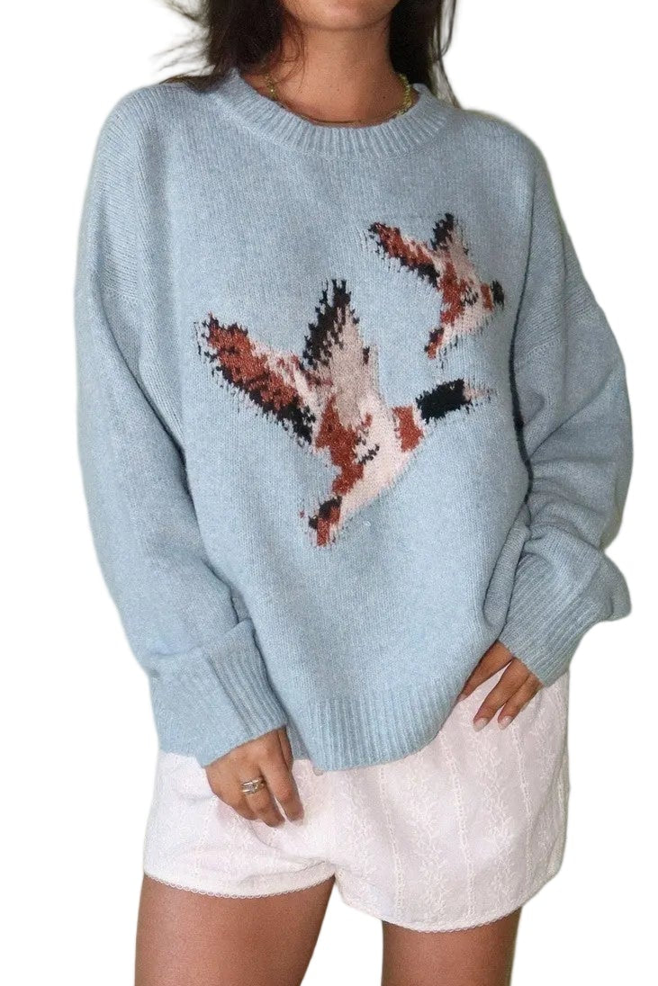 Woman wearing a light blue sweater with a design on a plain background
