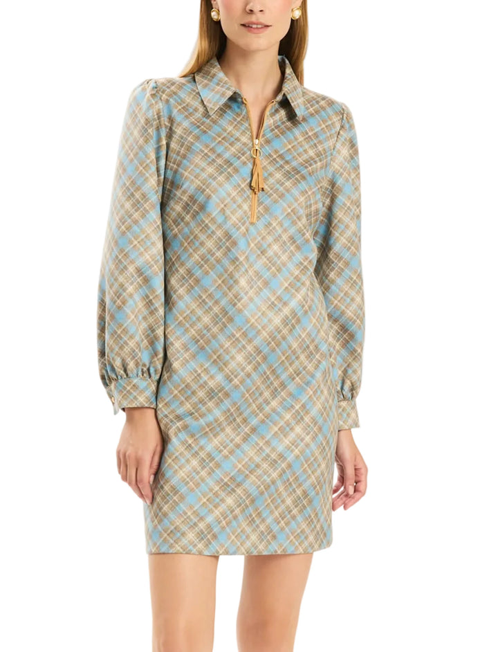 A woman modeling a long-sleeve plaid shirt dress with a half-zip collar and tassel detail, in beige, light blue, and brown tones, against a plain white background.