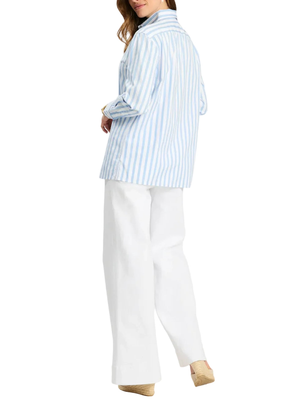 Woman wearing a light blue striped shirt and white pants on a white background