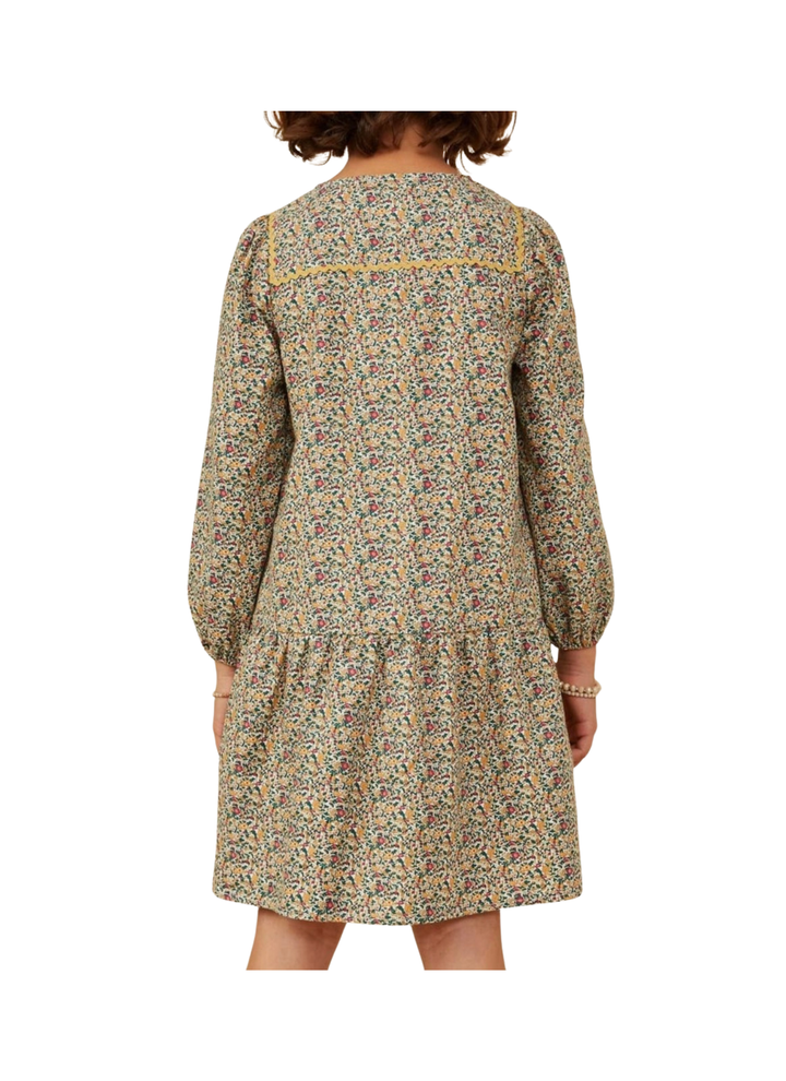 A child wearing a long-sleeve tiered dress with a dense multicolor floral print, shown from the back against a plain white background.