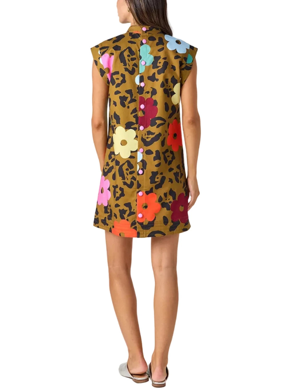 A woman shown from the back wearing a sleeveless brown leopard-print dress with a colorful floral pattern and a buttoned back, photographed against a light gray studio background.