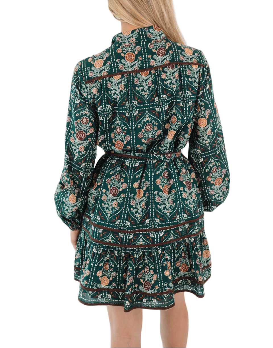 Step into autumn style with this hunter green multi-print dress, featuring long sleeves, a button-up neckline, & an adjustable tie belt for a flattering fit. Accented with brown embroidery trim detail, it channels effortless charm with a hint of ranch lifestyle. The perfect piece for autumn outings, weekend plans, & golden-hour strolls!