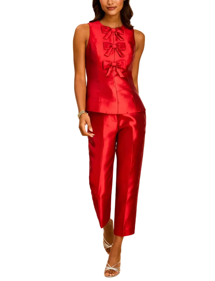 A woman modeling a bright red satin sleeveless vest and matching cropped pants set against a plain beige studio background.