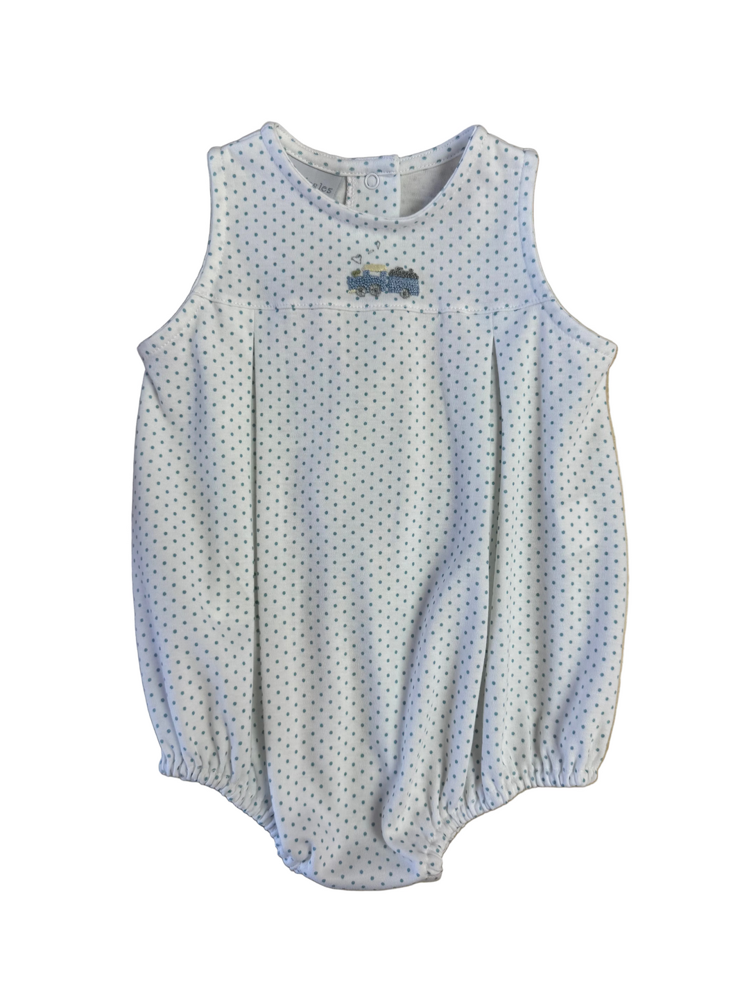 White baby romper with blue polka dots on a wooden surface