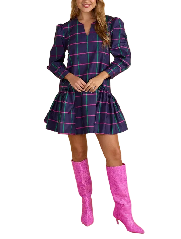 A woman modeling a short plaid dress with puff sleeves and a flared skirt, paired with bright pink knee-high boots, against a solid beige studio background.