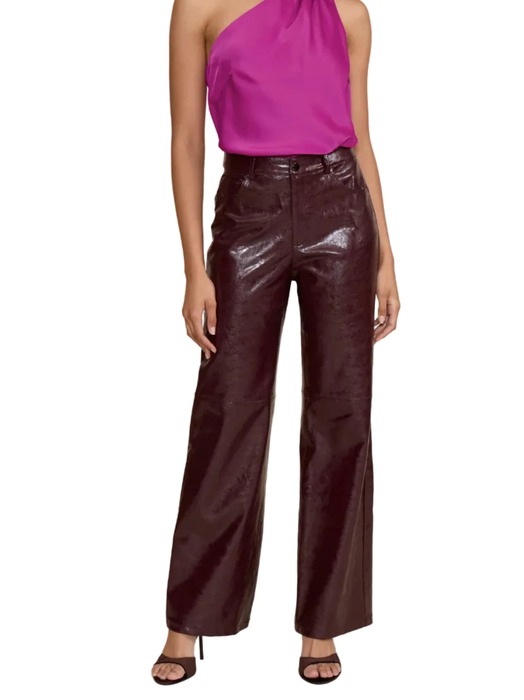 A model wearing high-waisted, wide-leg pants in a glossy, deep burgundy faux-leather material, paired with a pink top and black heeled sandals, against a solid beige background.