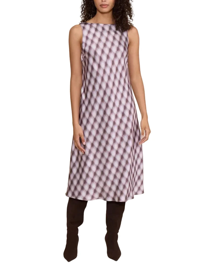 A woman modeling a sleeveless A-line midi dress with a pink and white wavy geometric pattern, paired with dark brown knee-high boots, against a solid beige studio background.