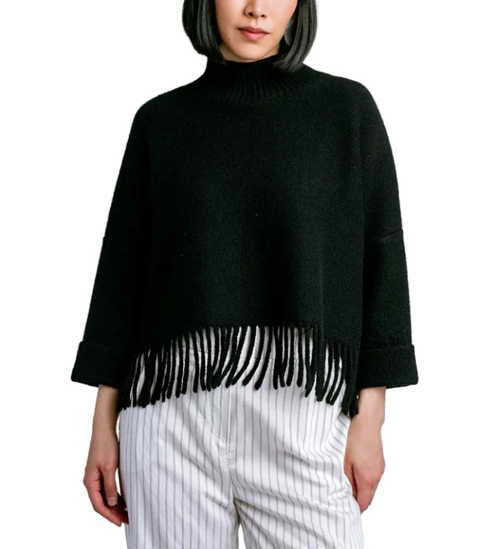 Person wearing a black fringe sweater against a light gray background