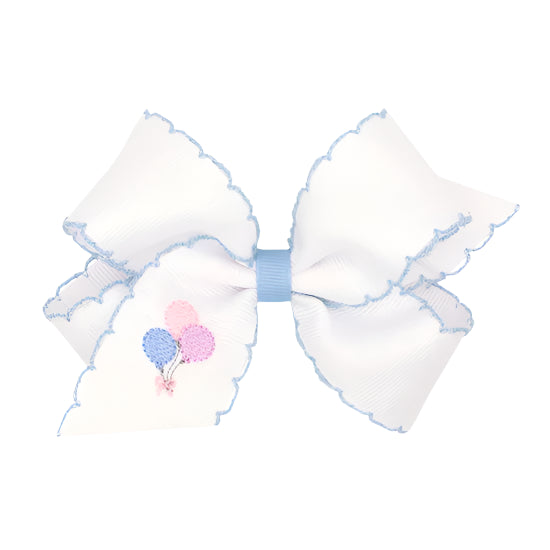 A medium grosgrain hair bow with moonstitch edge and birthday girl balloon embroidery in pastel colors.