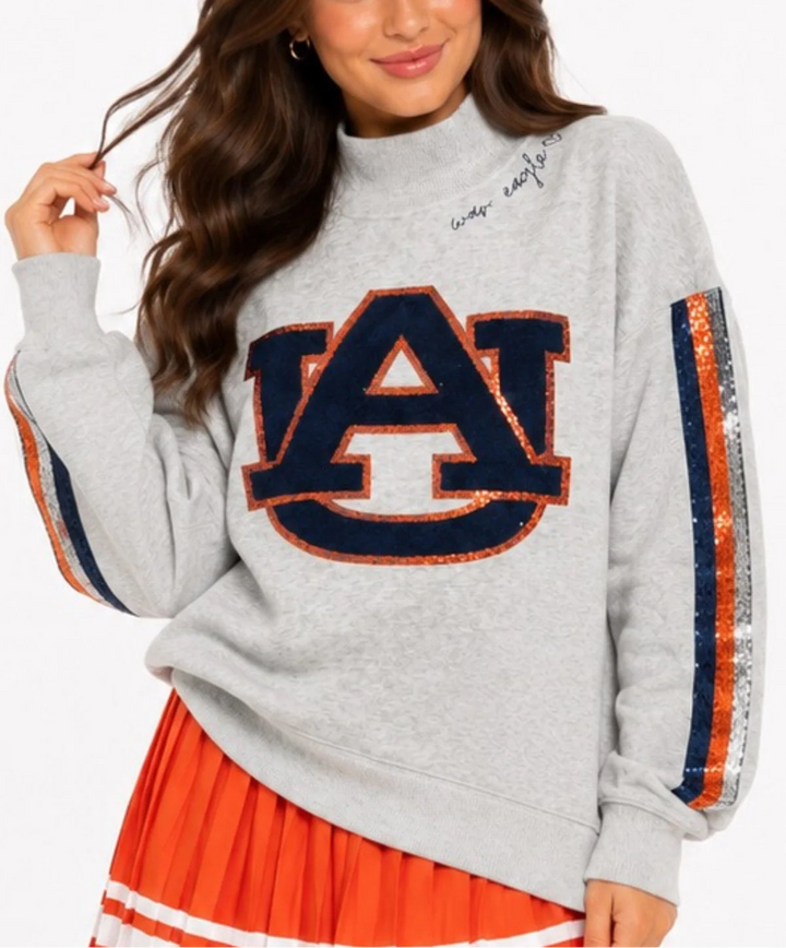 This is an Officially Licensed Collegiate Product
Soft gray mock neck sweatshirt featuring a bold Alabama elephant and “A” appliqué for a classic collegiate look
Eye catching sequin stripe detailing down each sleeve adds just the right amount of sparkle and contrast
Crafted from soft cotton Terry sweatshirt material 
Material: 80% Cotton, 20% Polyester
STYLE NOTE: This sweatshirt is made to fit oversized. You should purchase your normal size if you want the oversized look and fit. If you want a more fitted 