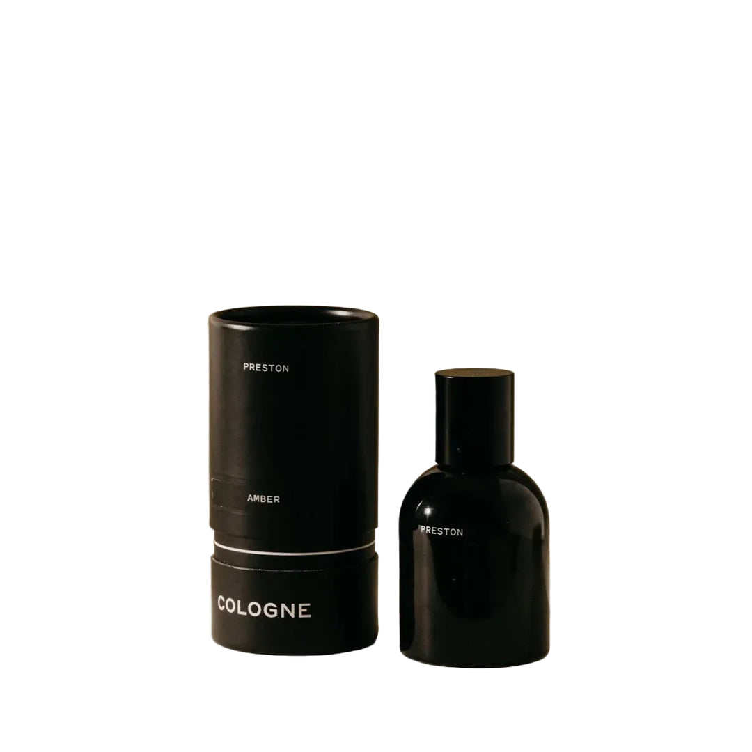 Black cologne bottle and cylindrical container on a beige background