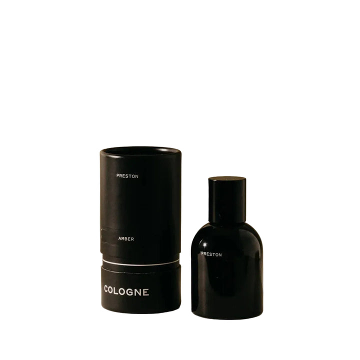 Black cologne bottle and cylindrical container on a beige background