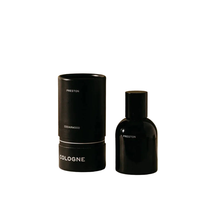 Black cologne bottle and cylindrical container on a beige background