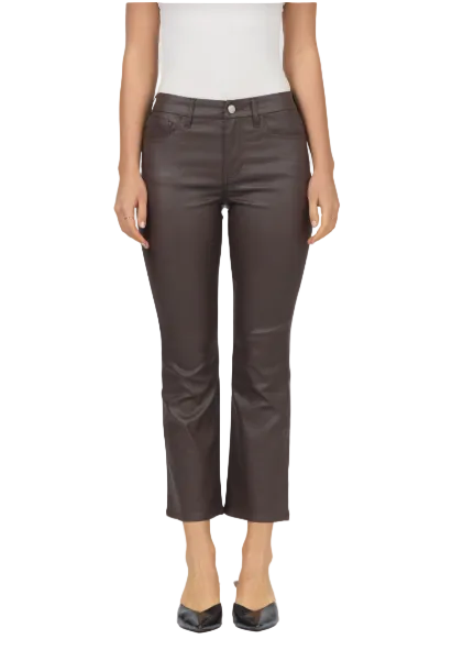 A model wearing dark brown faux-leather cropped pants, a white top, and black pointed-toe heels, shown against a light gray studio background.