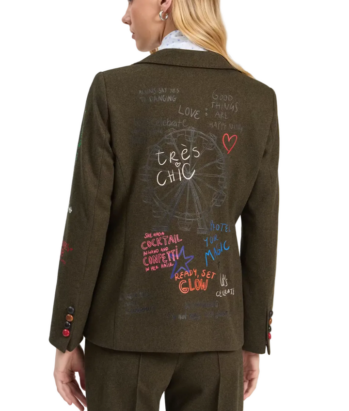 An olive green blazer with colorful graffiti-style text and drawings on the back, shown on a model from behind against a light gray studio background.