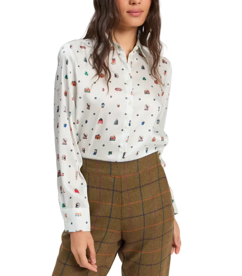 A woman wearing a white long-sleeve button-up blouse with a small multicolor allover print and brown plaid trousers, photographed against a light gray studio background.