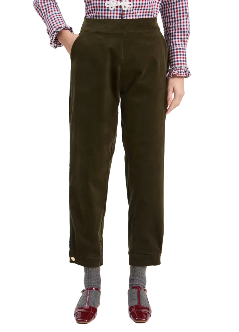 A model is shown from the waist down wearing dark olive green corduroy trousers, a red and white gingham shirt, gray socks, and burgundy Mary Jane shoes, against a plain light gray background.