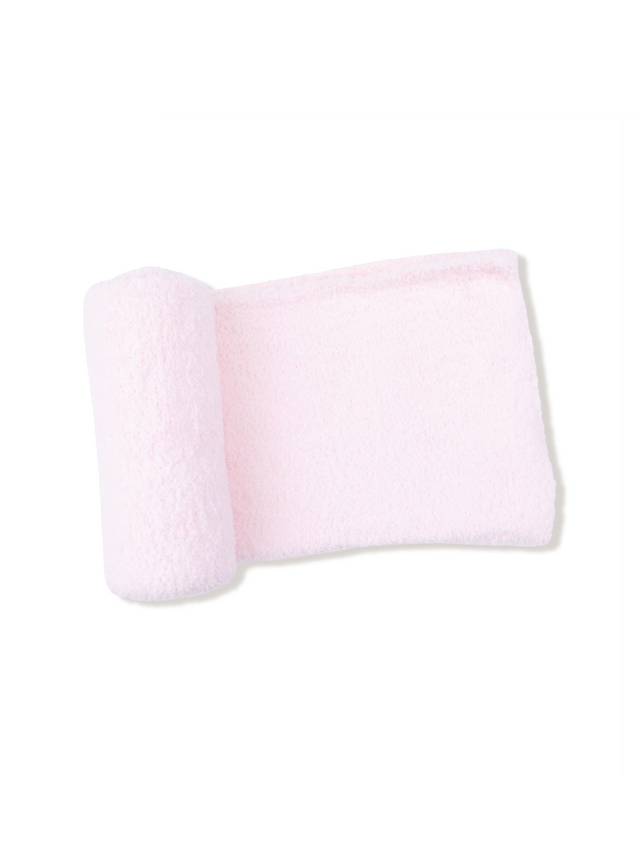 A light pink plush bath towel with a rolled corner, displayed on a clean white background with a faint drop shadow.