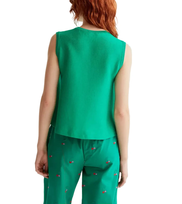Person wearing a green sleeveless top and pants on a light gray background