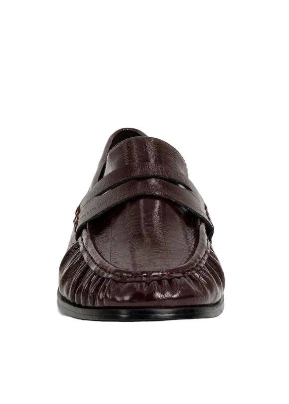Meet the Tokyo Loafer in a deep wine hue an elevated take on a timeless essential. Crafted in a smooth leather-like material with a polished finish, this style brings a refined pop of color while keeping a classic, structured silhouette. The traditional penny loafer design is enhanced with subtle gathered detailing along the vamp, adding texture and dimension. 