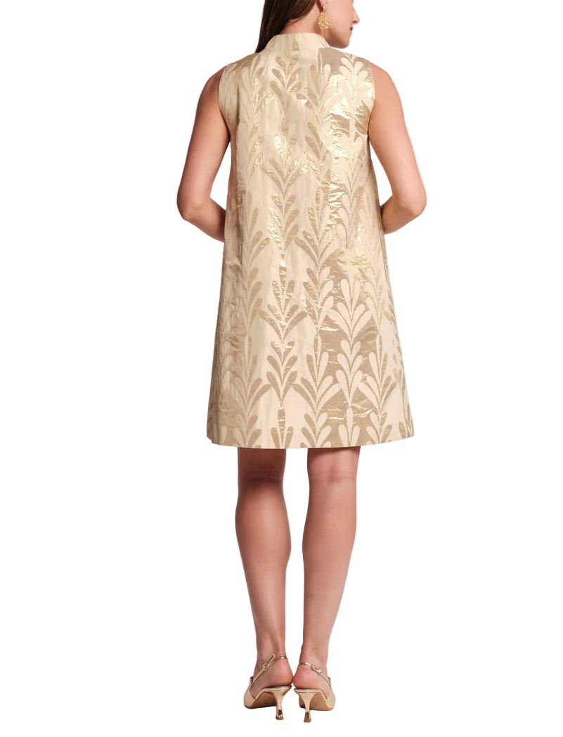 Woman wearing a beige sleeveless dress with a leaf pattern on a white background