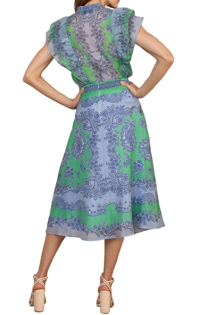 Woman wearing a patterned dress against a wooden wall.