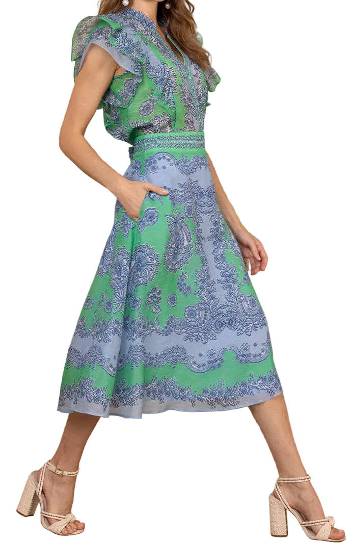 Woman wearing a patterned top and dress with green and blue design on a white background