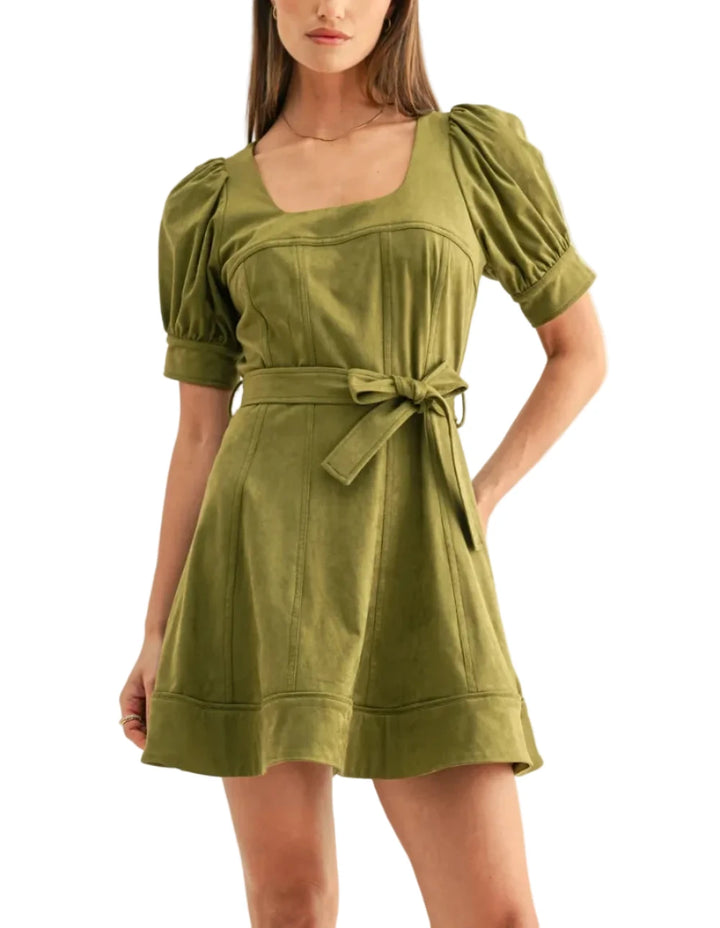 Crafted from a premium faux suede fabrication in a rich, earthy olive colorway, the dress offers a velvety, matte finish that enhances its sculpted silhouette. The design features a flattering, wide square neckline that meets a corsetry-inspired bodice detailed with vertical seam panels to elongate the frame. 
