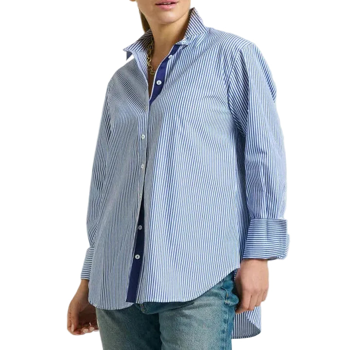 Woman wearing a blue and white striped shirt with rolled-up sleeves on a light gray background
