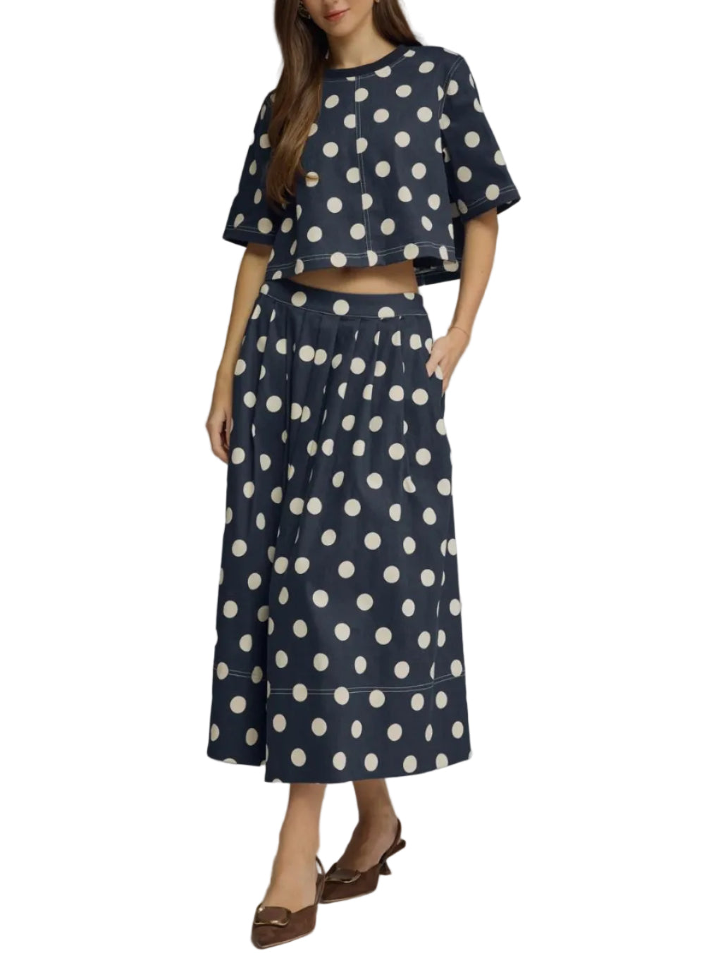 Woman wearing a navy blue outfit with white polka dots on a gray background