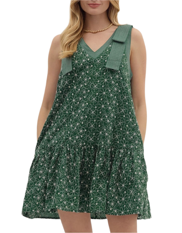 Floral embroidered sleeveless ruffle hem mini dress featuring exposed stitch detail shoulder bow detail and neck. Pockets at sides. Lined. Woven. Non-sheer. Lightweight.