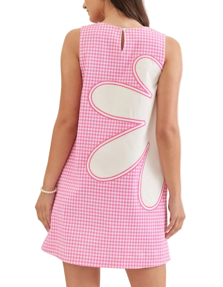 Woman wearing a pink checkered dress with white heart shapes on a plain background