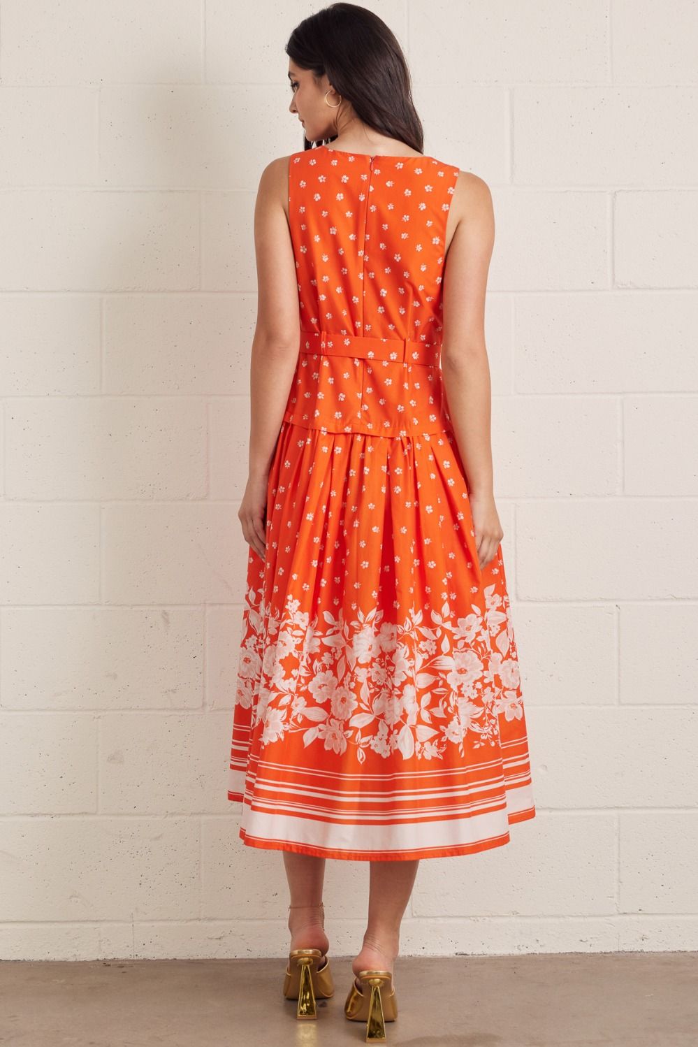 Floral sleeveless midi dress featuring self-belted waist and border print. Back zipper closure. Lined. Woven. Non-sheer. Lightweight.