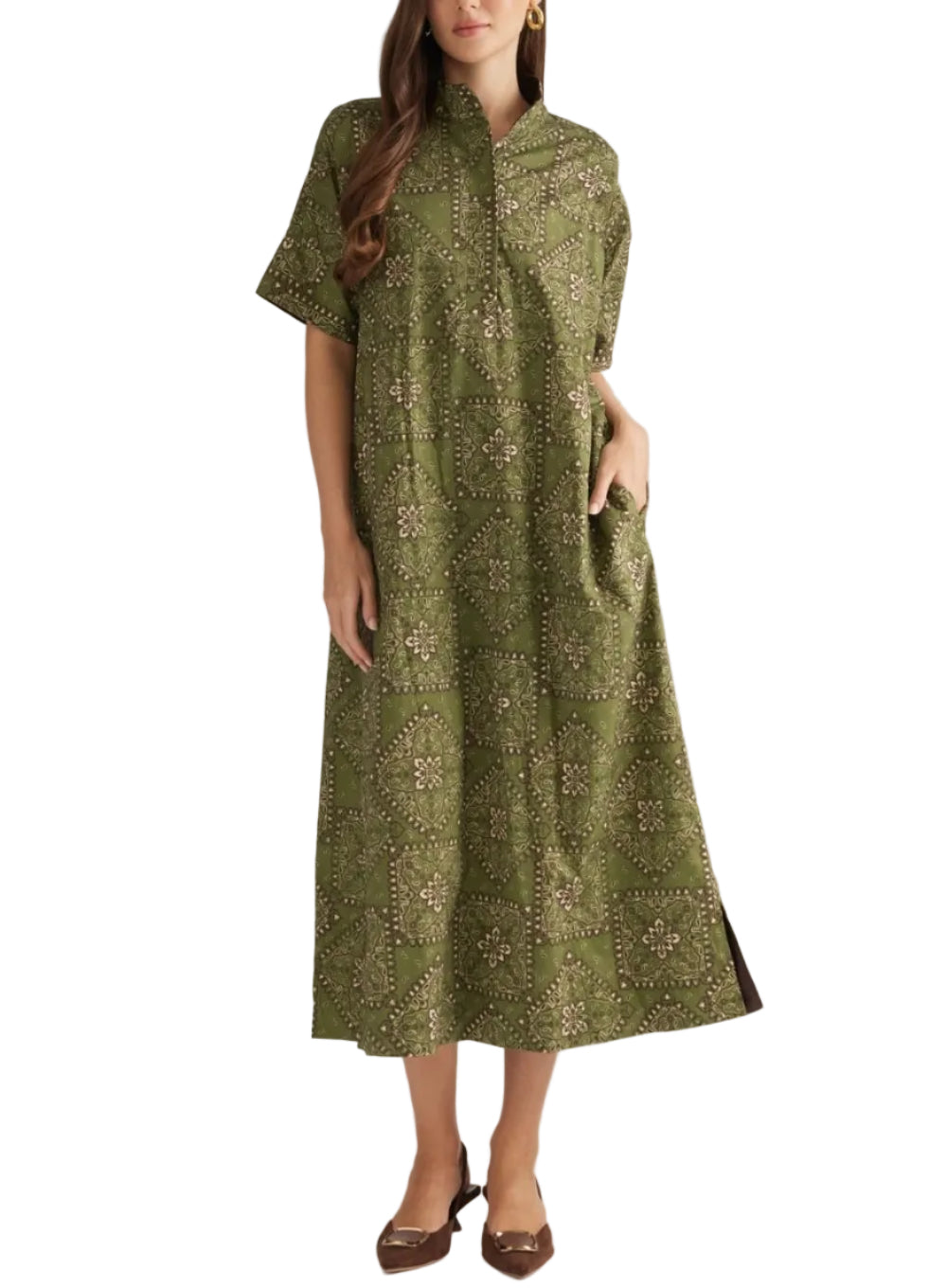 A woman modeling a short-sleeved olive green midi dress with a beige and brown geometric pattern, standing against a plain light gray studio background.