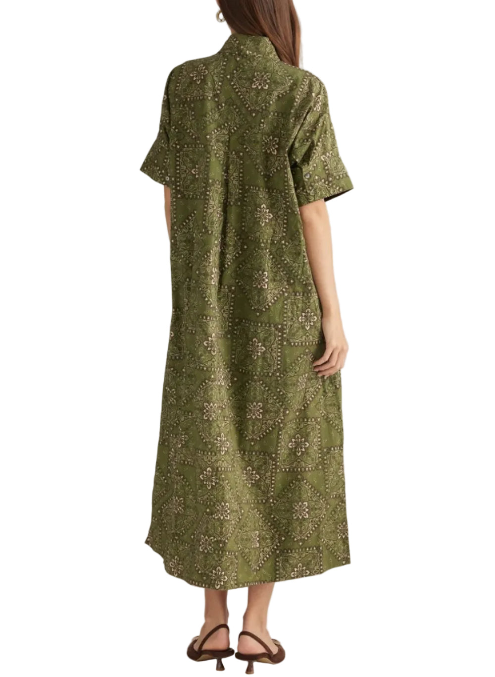 A woman viewed from the back wearing a short-sleeve olive green dress with a dense beige and brown floral block print, paired with brown strappy sandals against a solid light gray background.