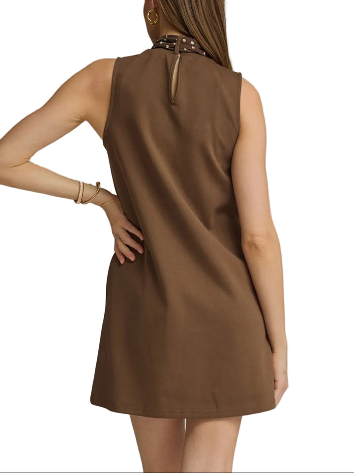The Isla Sleeveless Mini Dress combines effortless elegance with versatile styling. This lightweight piece features a flattering sleeveless silhouette perfect for warm weather, paired with an attached self-tie neck scarf that lets you customize your look. Wear the scarf tied at the neck for a polished finish, or drape it loosely for a relaxed vibe. Ideal for casual outings, weekend brunches, or layered styling. The mini length offers a modern, playful cut that works year-round with the right accessories.