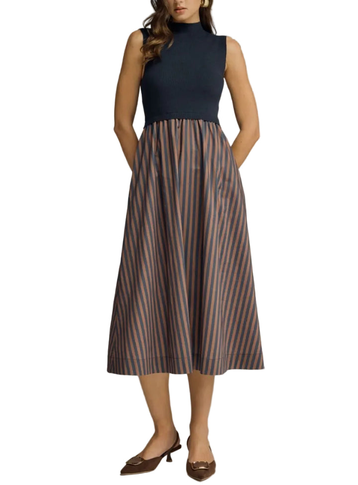 Woman wearing a sleeveless dress with a striped skirt on a gray background