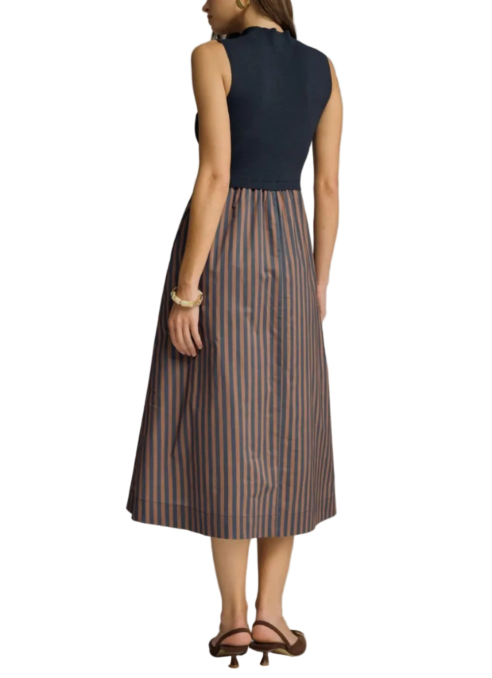 Woman wearing a black top and striped skirt against a gray background