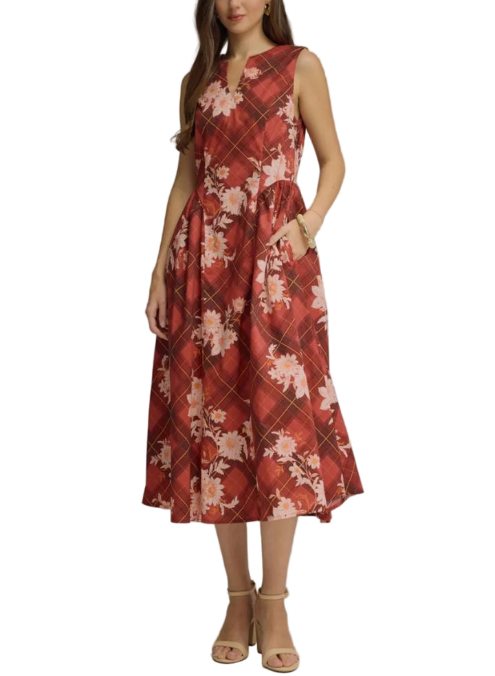 A woman modeling a sleeveless midi dress with a red and pink floral argyle pattern, standing against a neutral gray studio background.