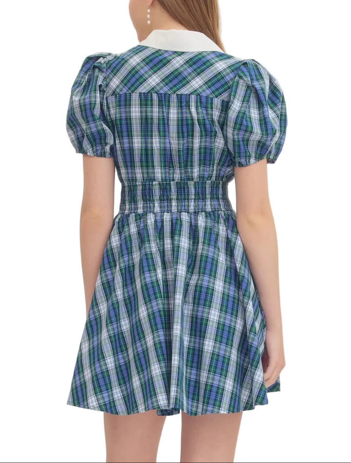 Plaid short puff sleeve mini dress featuring contrast collar. Button closure at front. Smocked waist. Side pockets. Lined. Woven. Non-sheer. Lightweight.