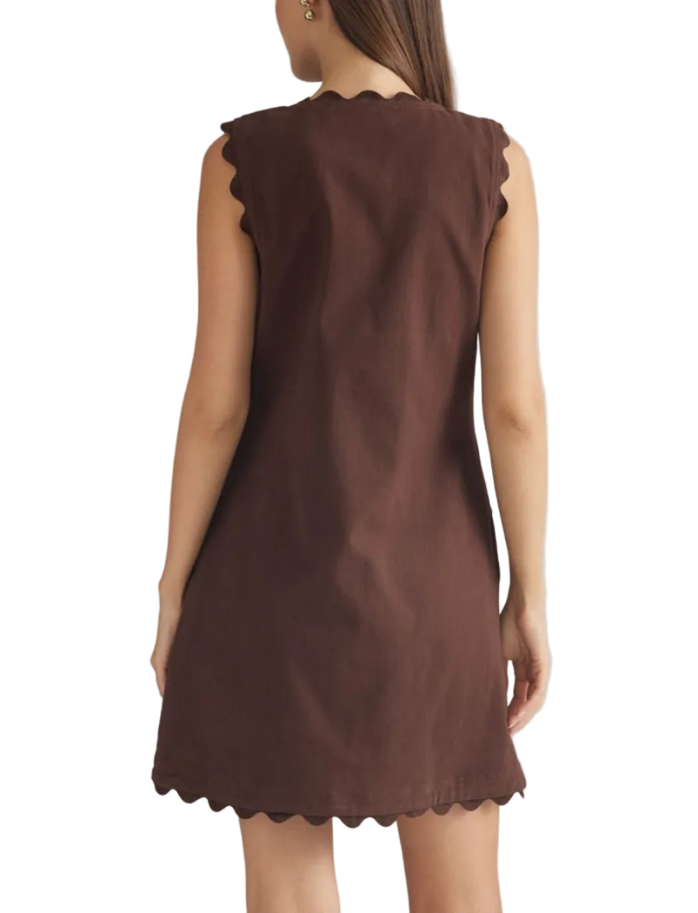 A woman shown from the back wearing a sleeveless brown dress with scalloped edges, photographed against a plain light gray studio background.