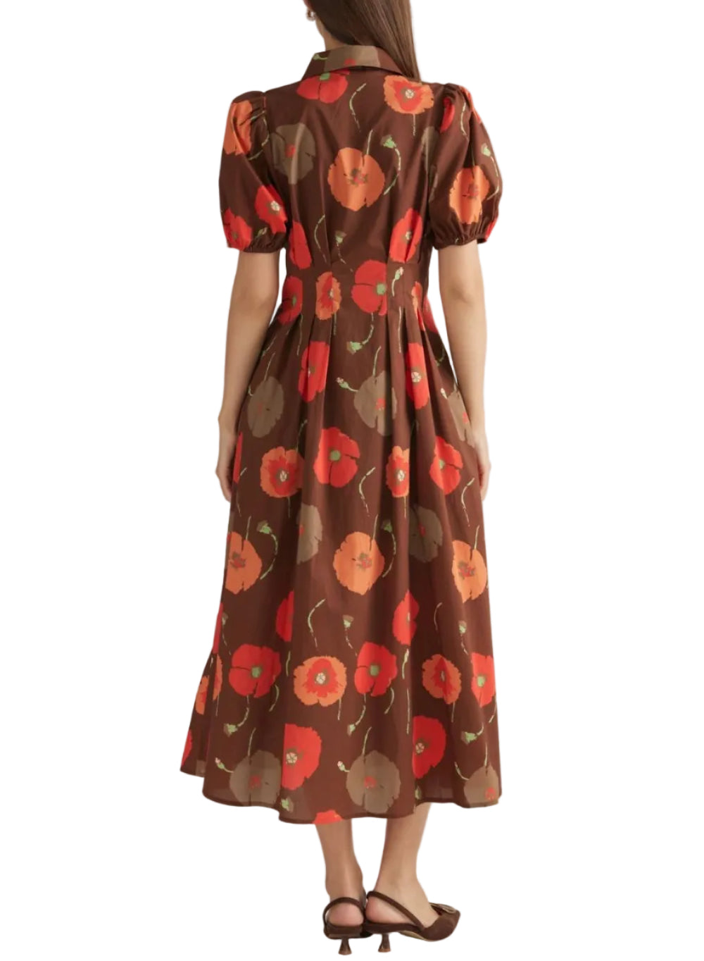 A woman viewed from behind wearing a brown midi dress with a red and orange poppy floral print, short puff sleeves, and a collared neckline, paired with brown strappy heels against a light beige studio background.