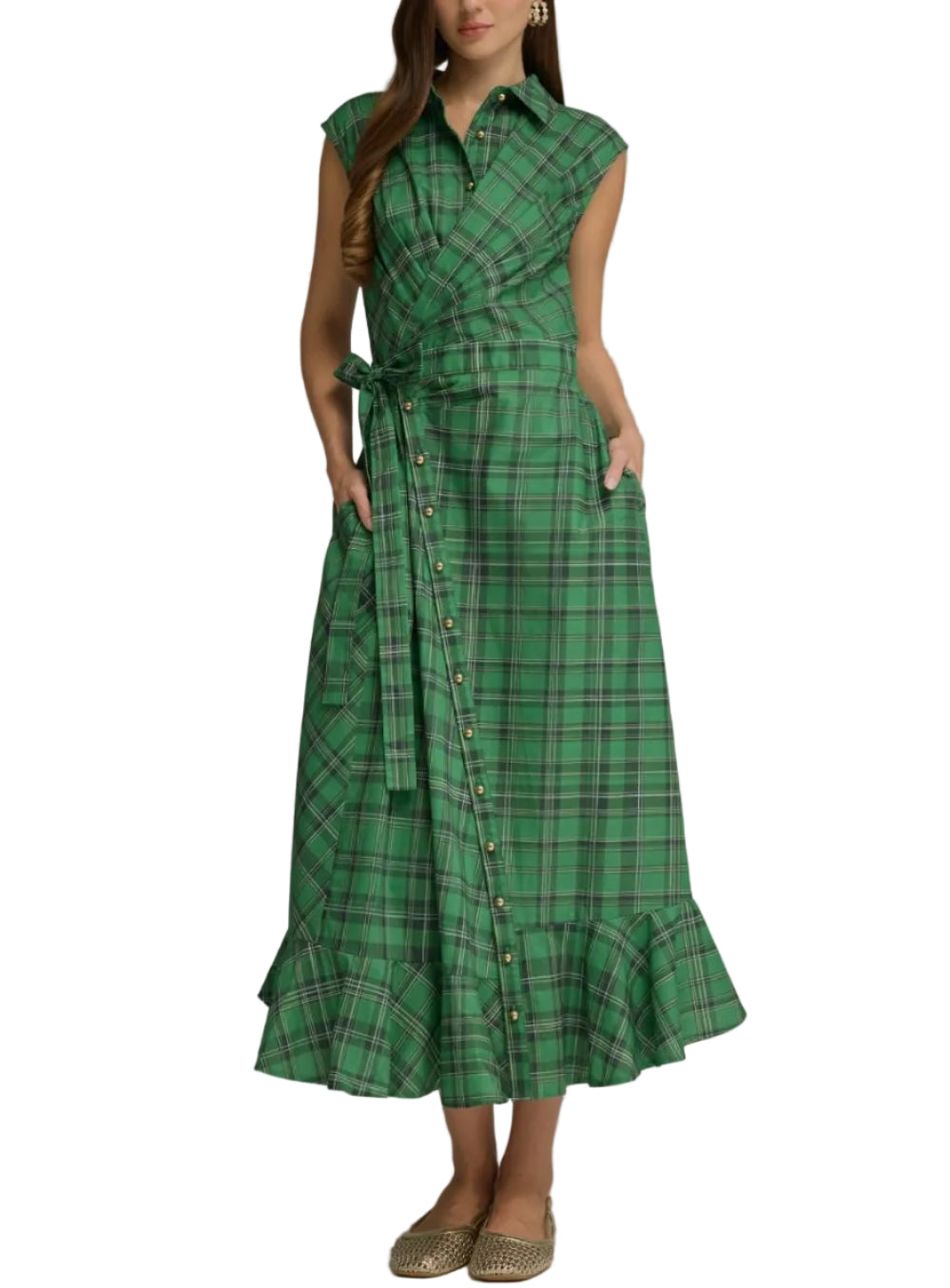 A woman modeling a green plaid midi dress with a wrap-style front, button details, side pockets, and a tie belt, photographed against a neutral gray studio background.
