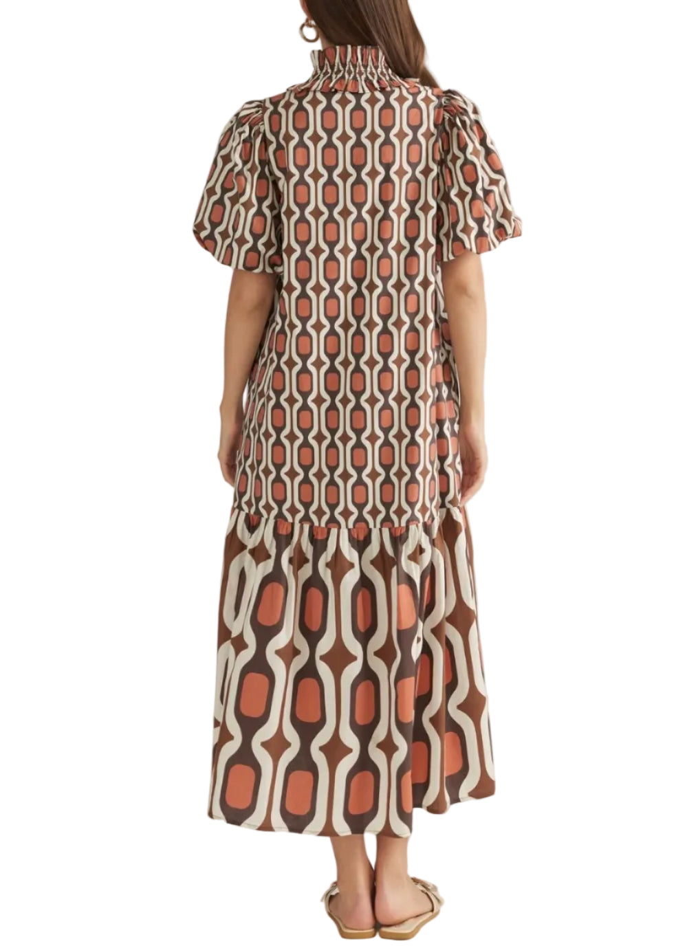A woman viewed from the back wearing a short-sleeve midi dress with puff sleeves and a high smocked neckline. The dress features a geometric pattern in rust orange, brown, and off-white.